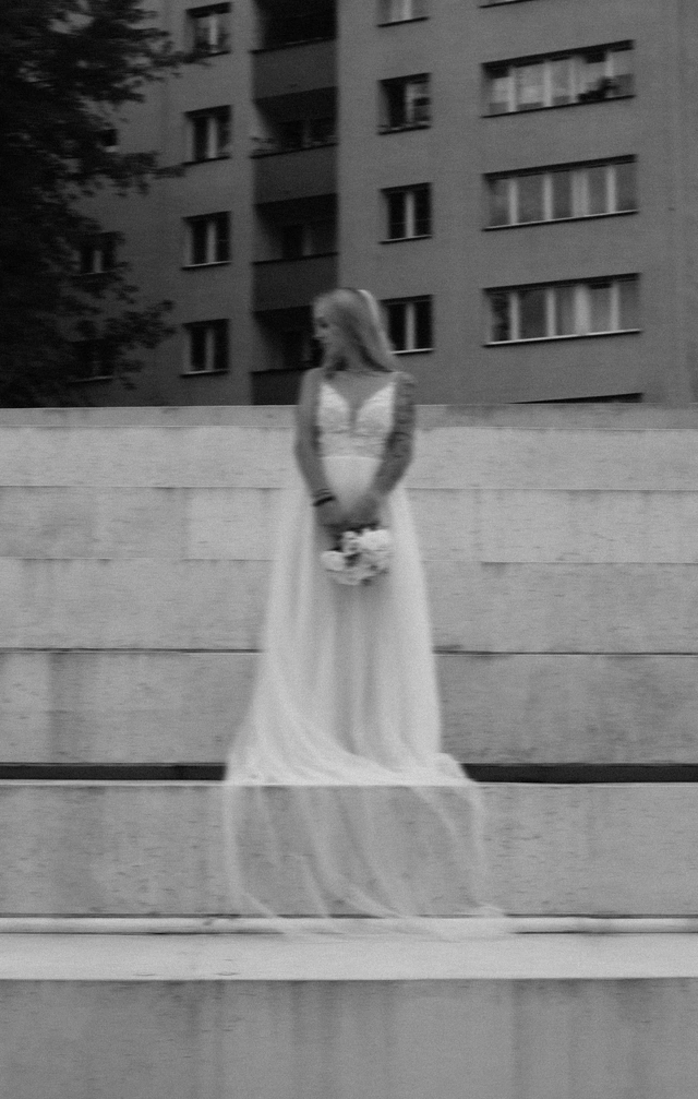 Czarno-biała fotografia panny młodej z welonem na miejskich schodach