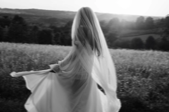Czarno-biała fotografia panny młodej obracającej się z rozwianym welonem