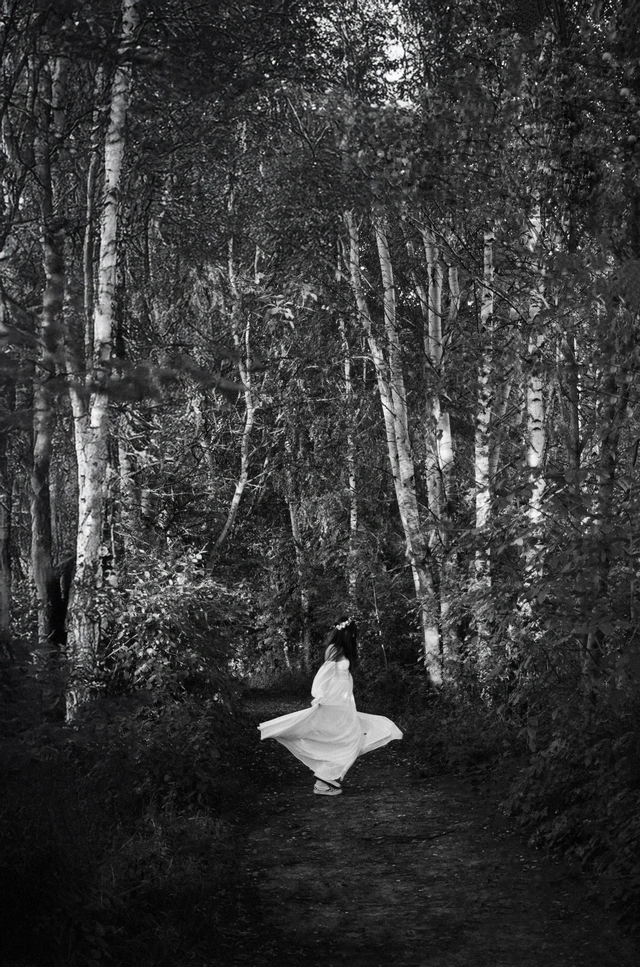 Czarno-biała fotografia panny młodej obracającej się na ścieżce w lesie